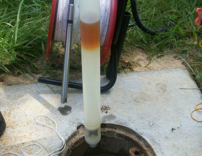 Phase separated hydrocarbons (gasoline/kerosene mixture) floating atop a groundwater sample retrieved from a monitoring well.